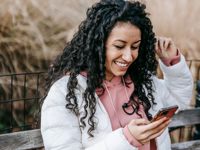 Mujer sonriendo mientras revisa su celular