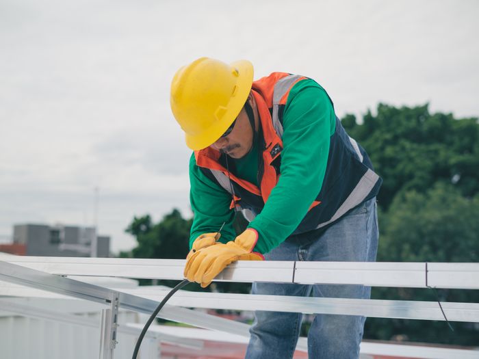 Instalador con casco montando la estructura de paneles solares en una azotea