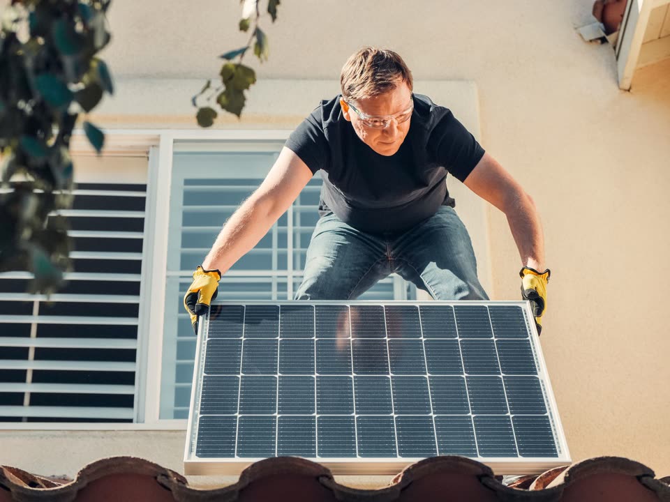 Instalador colocando un panel solar en el techo de una casa